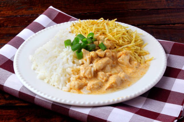 Chicken stroganoff, is a dish originating from Russian cuisine that in Brazil is composed of sour cream with tomato extract, rice and potato chips, on rustic wooden table.